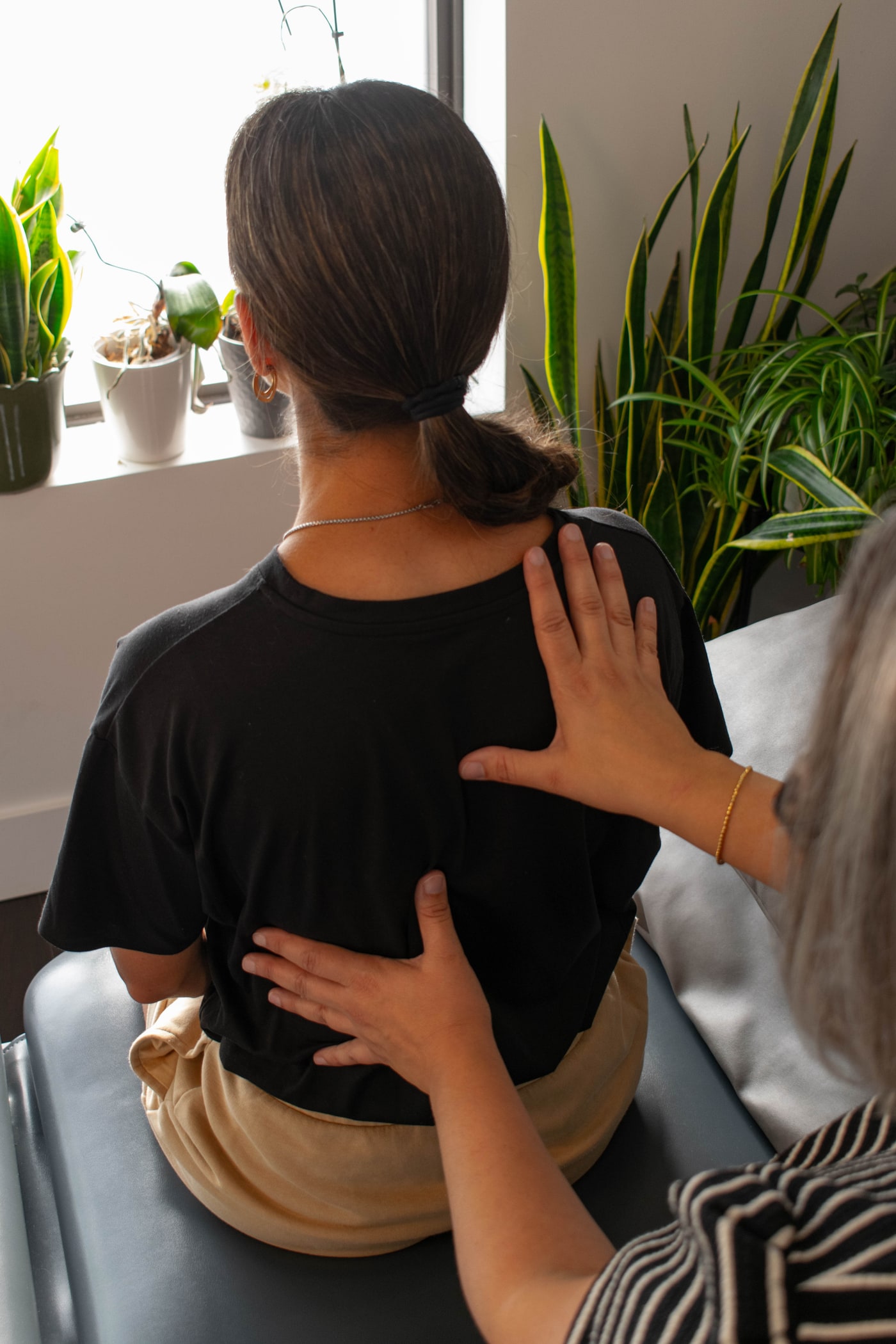 Melissa using both hands to assess a patient's upper and mid-back mobility